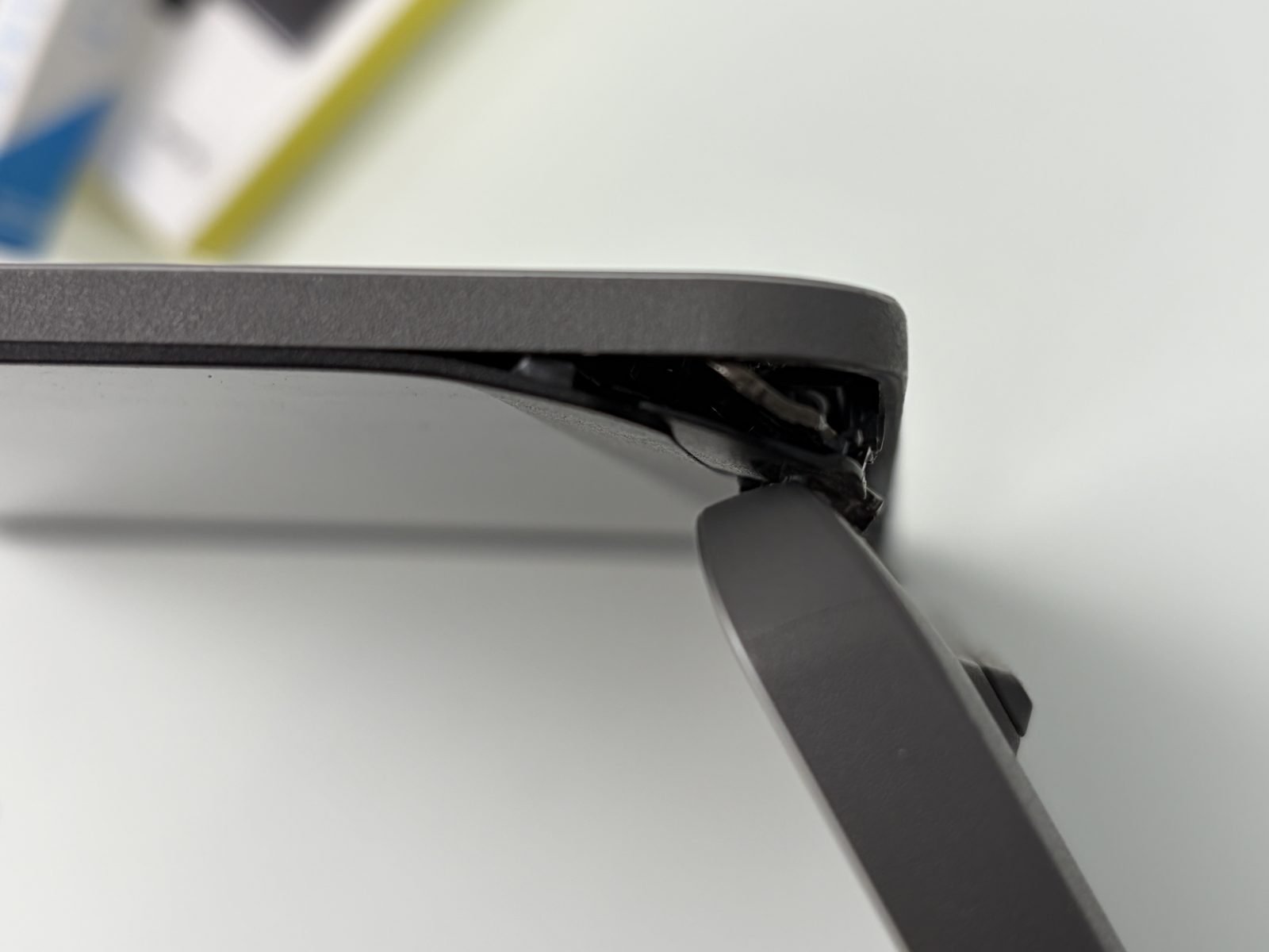 Detail van de gescheurde kunststof behuizing rond het laptopscharnier, waar de bevestigingspunten zijn uitgescheurd