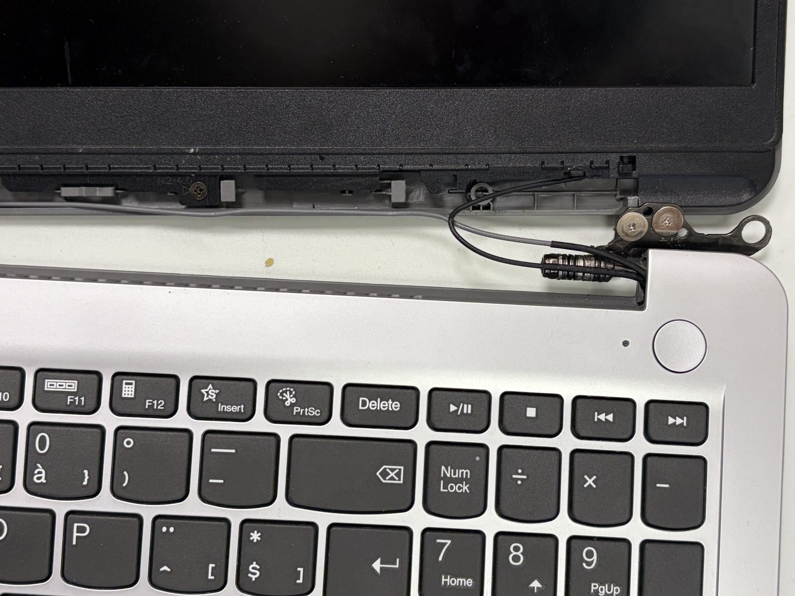 Close-up van het laptopscharnier met de schermkabel die er vlak langs loopt, zichtbaar bij een geopend toestel
