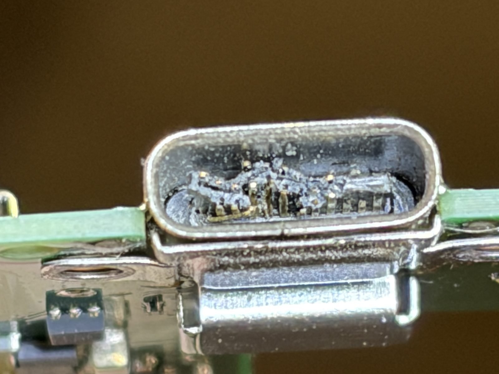 Close-up van de beschadigde USB-C-oplaadpoort van een Nintendo Switch OLED, met vuil en verbogen contactpinnen in de poort