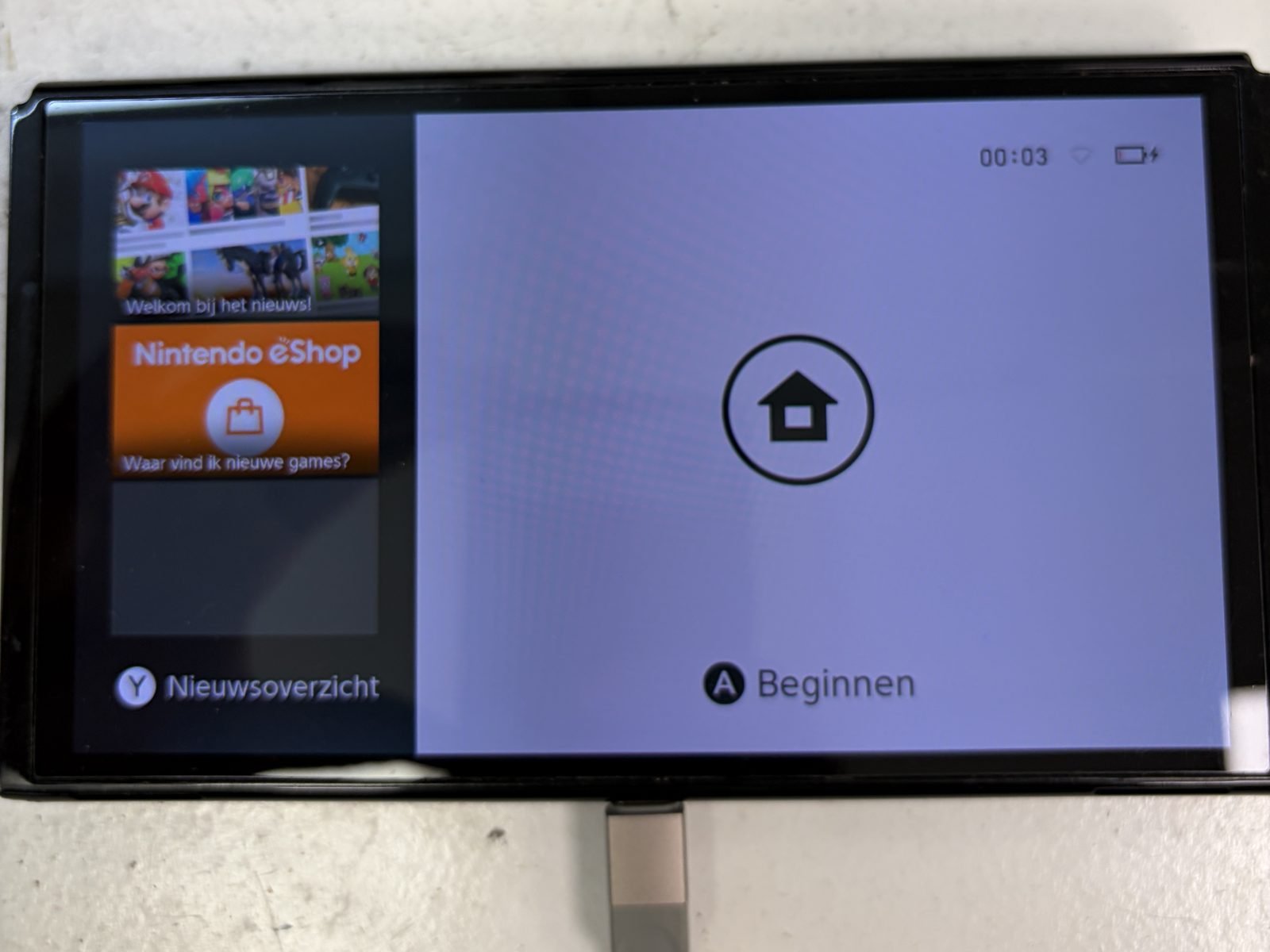 De herstelde Nintendo Switch OLED staat aan en laadt op via de nieuwe USB-C-poort, met het laadsymbool rechtsboven in beeld