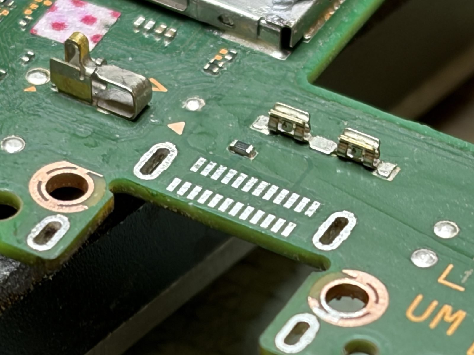 De kale soldeerpads op de printplaat van een Nintendo Switch OLED nadat de oude USB-C-poort is losgesoldeerd, alle pads onbeschadigd
