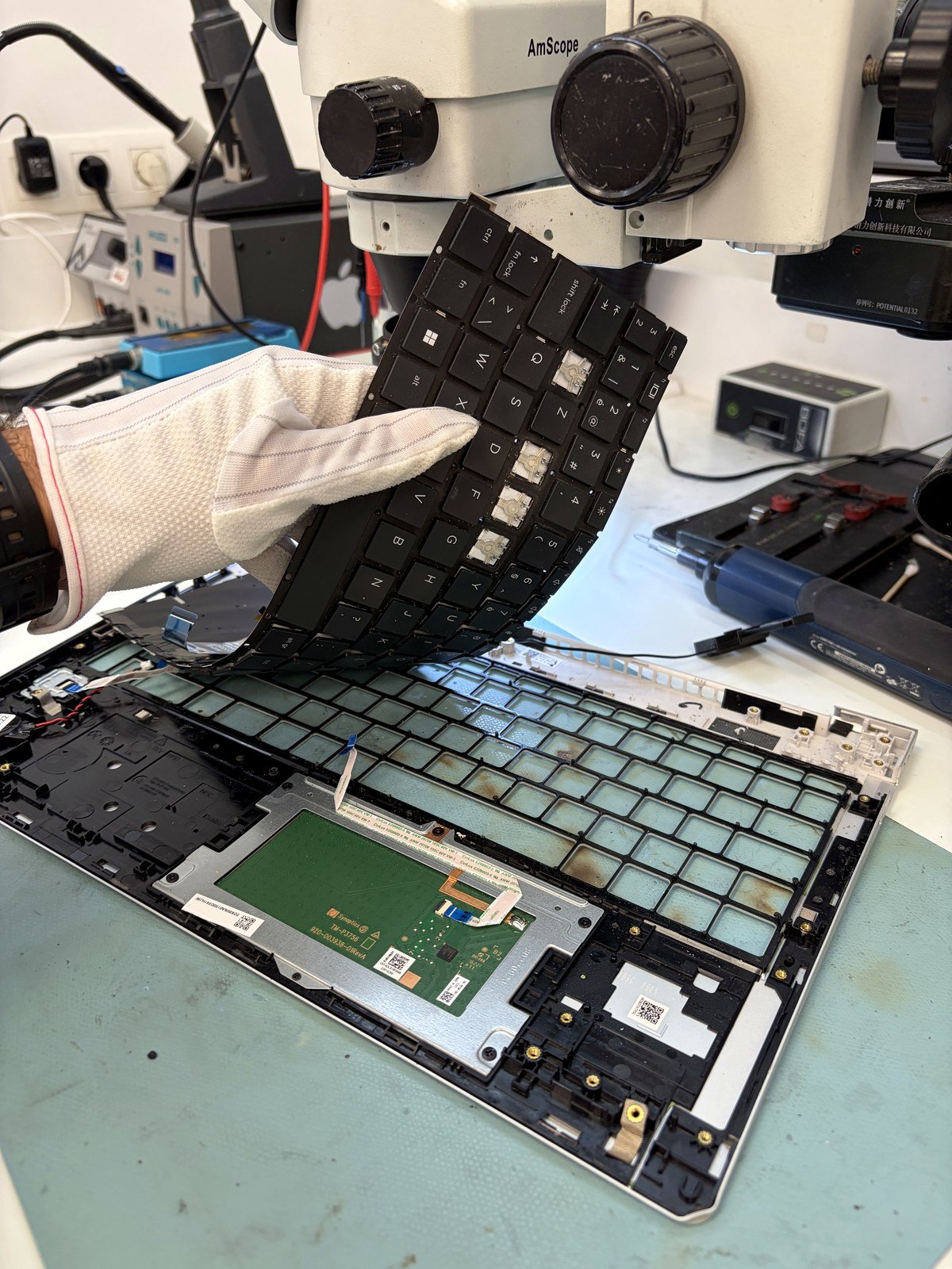 Het oude toetsenbord wordt losgekoppeld van het moederbord van een HP ProBook